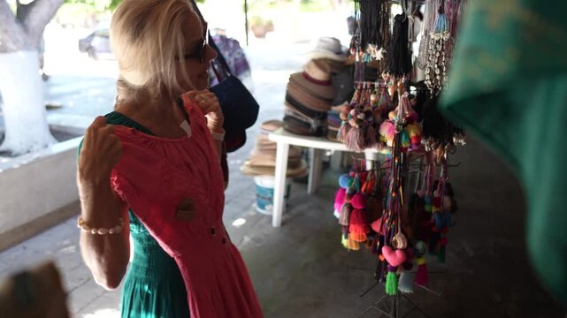 Mature woman explores options and checks outfits in clothing shop located in Loreto Baja California Sur Mexico as she shops for clothes.