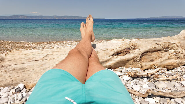 Man sunbathing on a rocky sea ocean beach.