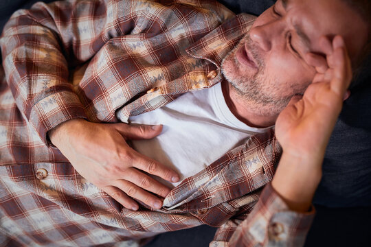 Man with heart problems, chest and abdominal pain at home measuring and checking pulse.