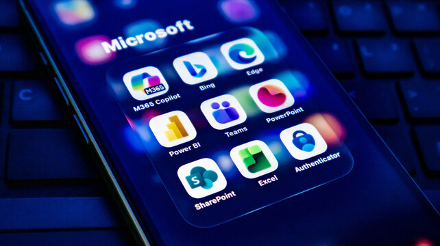 Closeup of a smartphone screen displaying various microsoft application icons including m365 copilot, bing, edge, teams, and powerpoint