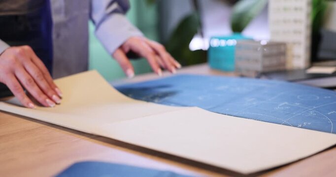 Woman engineer opens building drawings to show to manager in office. Skilled architect designers develop urban infrastructure in coworking slow motion