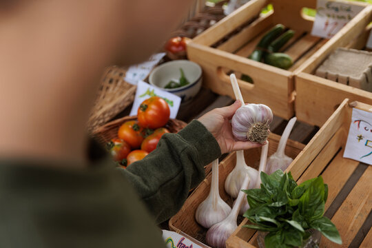 Person shopping for garlic and vegetables at a market in early fall