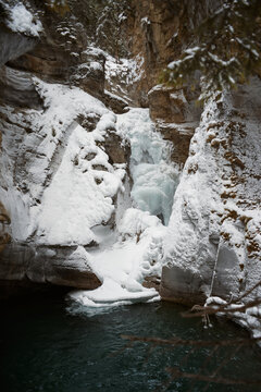Winter waterfall with ice and snow in a rocky canyon