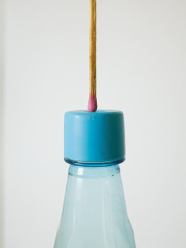 Matchstick balanced on a blue bottle cap conceptual minimalism