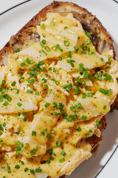 Close up scrambled eggs on a bread slice topped with parmesan cheese