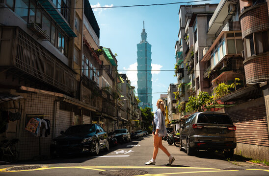 Woman crossing street with Taipei 101 in background