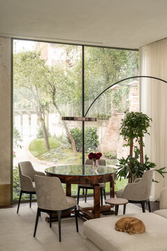 Dining table with glass top and flowers by window