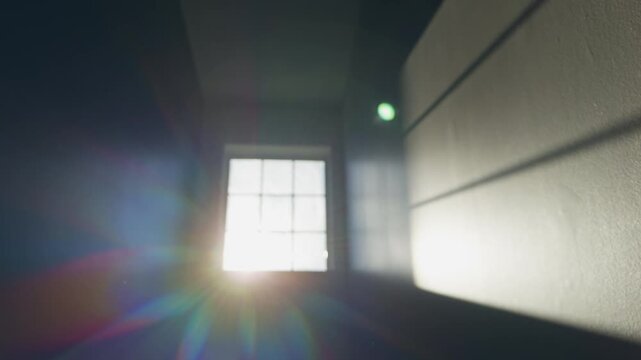 Sunlight streams into a room through a window. Shadows stretch across the walls. The atmosphere shows the start of a new day. Light fills the empty space