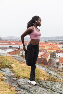 Active African Woman Stretching Leg During Outdoor Workout
