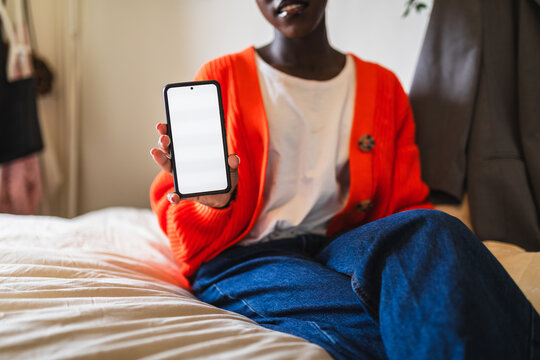 African Woman Showing Blank Smartphone Screen Sitting on Bed