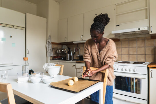 Woman Shaping Cookie Dough on Baking Sheet in Modern Kitchen