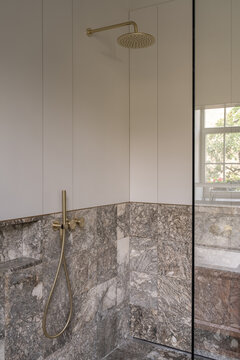 Minimal shower with brass fixtures and marble wall