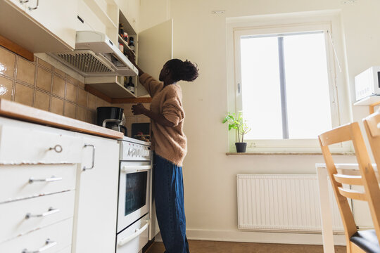 Woman Reaching for Top Cabinet in Modern White Kitchen