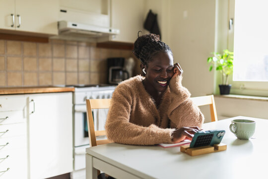 Happy Woman Watching Video Content on Smartphone in Kitchen