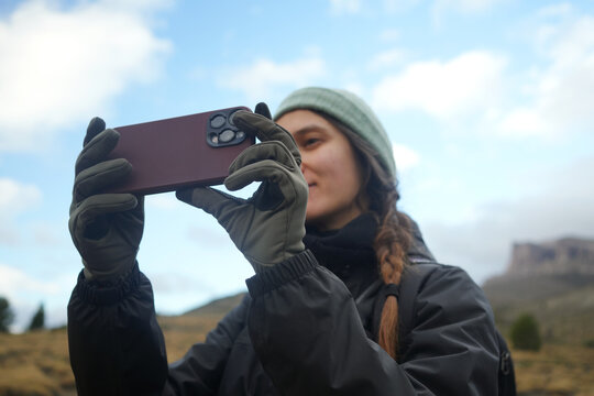 Woman Takes a Photo With Her Phone in Outdoor Setting During Day