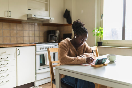 Student Taking Notes while Watching Online Lesson on Phone