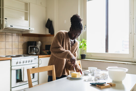 Woman Cutting Butter and Preparing Ingredients for Baking in Kitchen