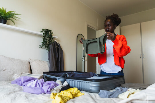 Black Woman Packing Clothes into Suitcase for Travel Trip