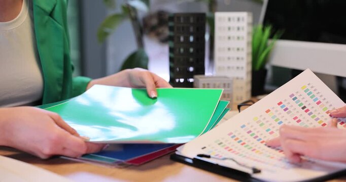 Female designers choose color palette for house interior design in office. Women decorators discuss material samples for building style in workplace