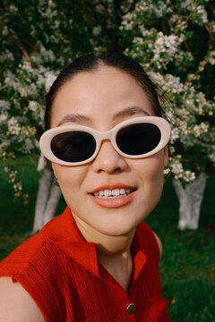 Smiling woman in sunglasses portrait with blooming trees