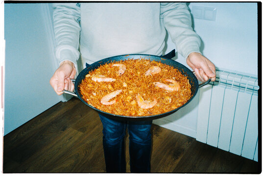 a man holds a pan of fideua typical of Spain, 35mm film