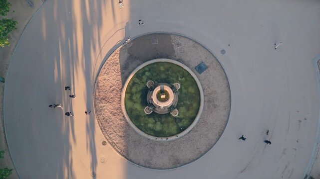Zenital drone shot zooming in slightly on a historic circular park fountain