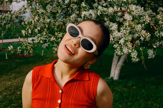 Smiling woman in sunglasses portrait with blooming trees