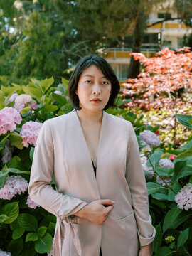 Non-binary model in pink blazer in garden