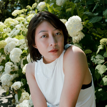 Non-binary person in front of hydrangea flowers