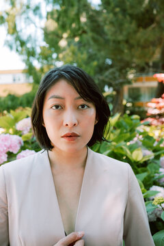 Non-binary model in pink blazer in garden 2