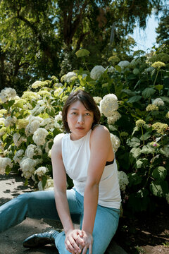 Non-binary person in front of hydrangea flowers 2