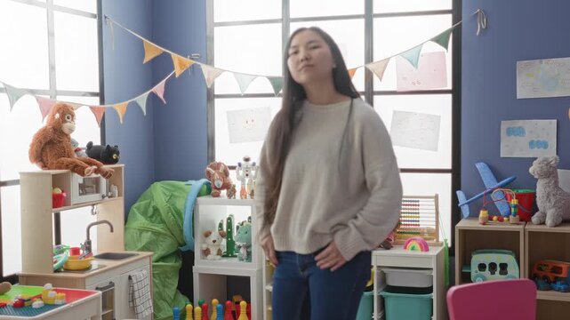 Woman with hands in pockets smiling beside stuffed toys and educational play items in a children's playroom inside a building; playful contentment.