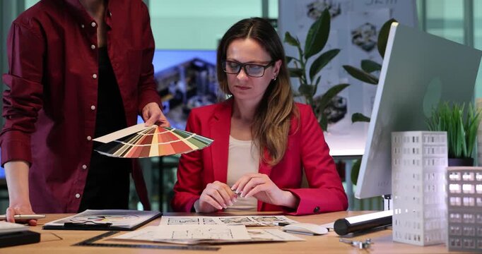 Architectural designers choose wall colors from decorative palette. Women select harmonious shades for apartment renovation. Slow motion