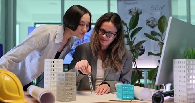 Architectural designer creates geometric sketches with compass. Women create elegant building design sketches on large sheets of paper. Slow motion