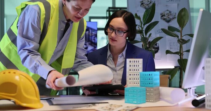 Builder shows construction drawings to professional architect. Construction worker discusses stages of multi-story building project. Slow motion