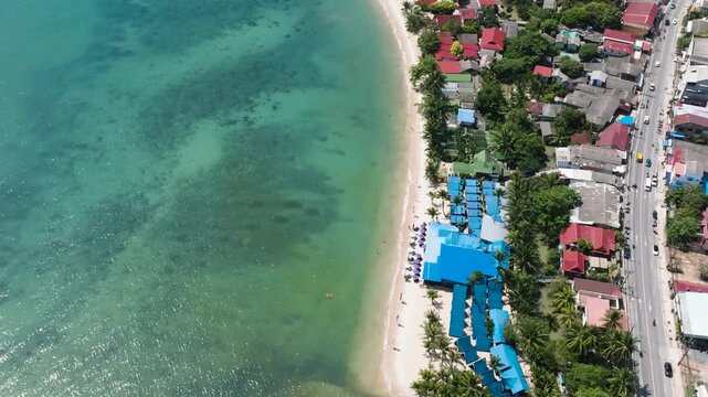 A beachside resort with colorful rooftops and turquoise sea along the coastline. Ko Samui, Thailand.