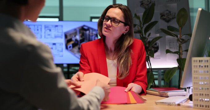 Blonde designer shows elegant wallpaper colors to client. Interior designer discusses sophisticated interior ideas for future apartment. Slow motion