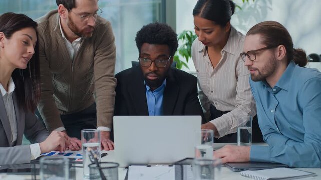 Multiracial business team five diversity managers talk discuss laptop problem at office meeting multiethnic women and men talking looking in computer screen discussing trouble with online working