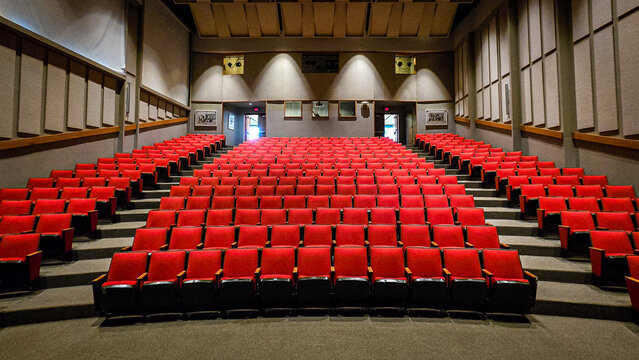 Empty movie theater auditorium with red velvet seats