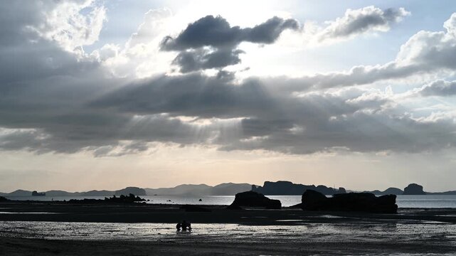 People crouch on tidal shore at Tubkaek Beach