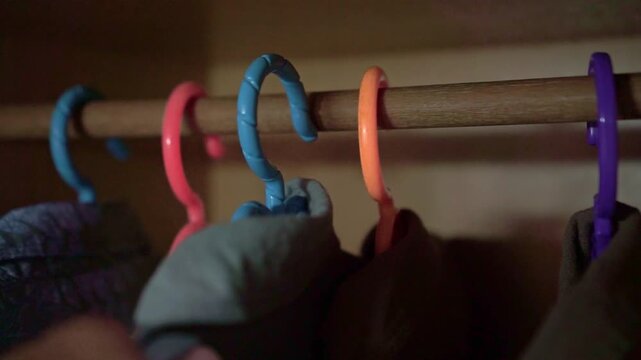a person hanging clothing in a closet, showcasing wardrobe organization, garment care, storage solutions, and tidy living habits.