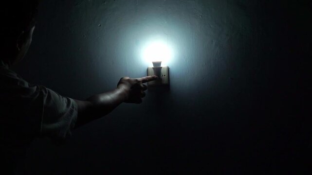 Person pressing a light switch to turn on illumination indoors. Home lifestyle, electricity usage, and energy efficiency concept.
