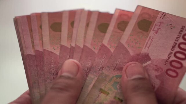 Person counting a stack of banknotes manually with hand, representing personal finance, budgeting, cash handling, income, expenses, and financial responsibility.