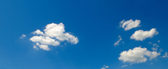 Obraz premium Bright blue sky panorama with sparse fluffy white clouds on a sunny day