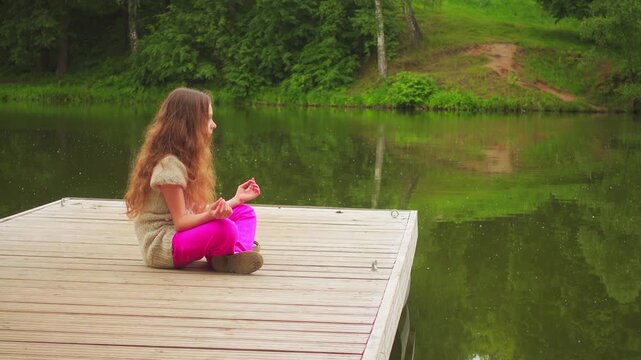 little girl is engaged in yoga on wooden bridge