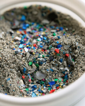 Microplastic particles gray sand laboratory dish close up environmental pollution colorful fragments separation waste analysis scientific sample plastic debris