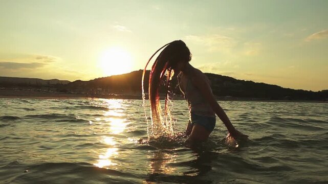 Little beautiful girl plays in warm summer sea