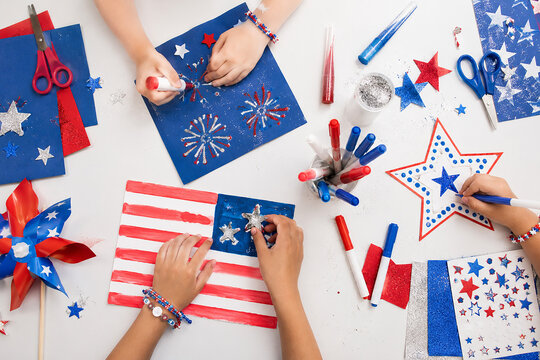 Children creating patriotic arts and crafts for independence day with red white and blue colors.