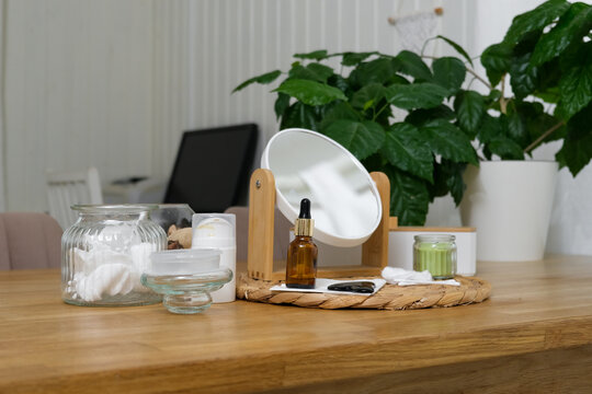 Vanity mirror with cream bottles, serum. Facial gua sha tool for skincare massage. Self care set desk. Feminine aesthetic. Beauty setting for selfcare routine. No people. Dressing table cosmetics
