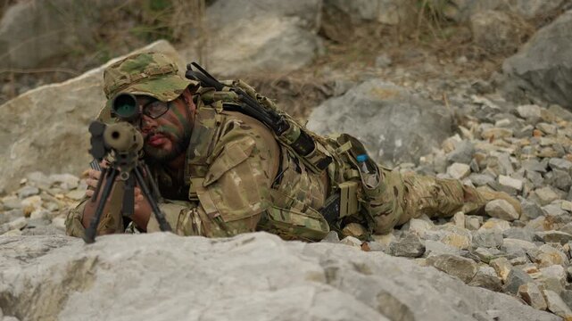 A special forces sniper with face paint lies prone on a rocky outcrop, providing overwatch and conducting reconnaissance during a covert military operation.